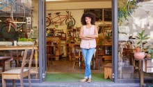 Woman standing happily in the entrance of her coffee shop